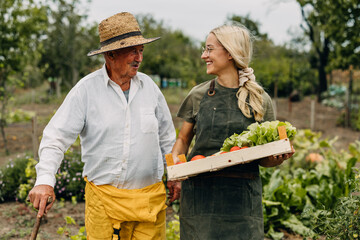 Young caucasian woman spending time with her granddad in the garden.