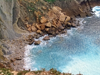 Rockslide of large boulders at the bottom of a coastal cliff due to erosion. Landslide with rockfall into the Atlantic Ocean at the Espichel Cape in Sesimbra, Portugal.