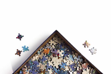 Top view of puzzle pieces in a box on a white surface with space for text