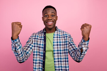 Fototapeta premium Photo of young crazy businessman raised fists up celebrate victory wearing smart casual checkered shirt isolated on pink color background