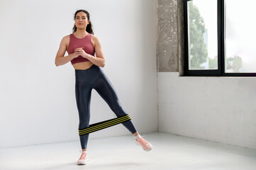 Focused athlete woman in activewear doing stretching work out with elastic band.