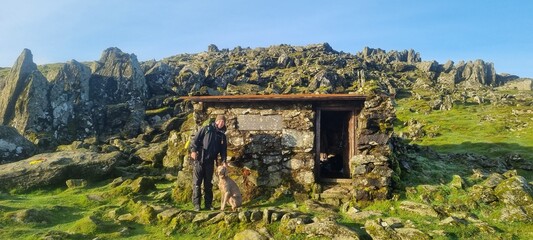 Hiker and Weimaraner dog at Foel Grach mountain shelter in the Carneddau mountain range in Eryri...
