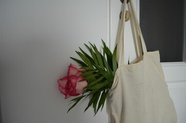 Tote bag with pink flowers hanging on the white door