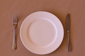 Top view of empty plate with metal fork and knife on the table