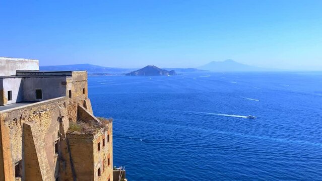 Amazing view from Procida Island (Isola di Procida) at the Tyrrhenian Sea in the Gulf of Naples crossed by many boats with wakes, Palazzo d'Avalos in the left foreground and Mount Vesuvius in the back