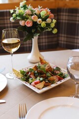 Bowl of Fattoush salad, with a variety of colorful ingredients and a glass of wine in a restaurant