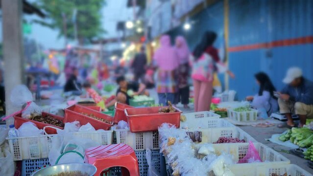 Kitchen spices and cooking ingredients are lined up and hung in containers at Indonesia's traditional morning market. Shoppers pass by and sellers offer their wares