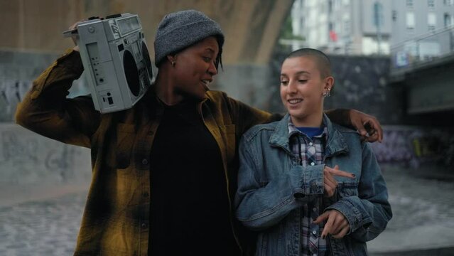 Happy multiracial women having fun dancing while listening to music with vintage boombox stereo