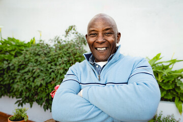 Naklejka na ściany i meble Happy senior African man gardening at home