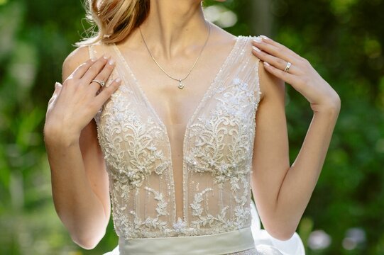 Beautiful young woman dressed in a white wedding dress standing in a picturesque setting.