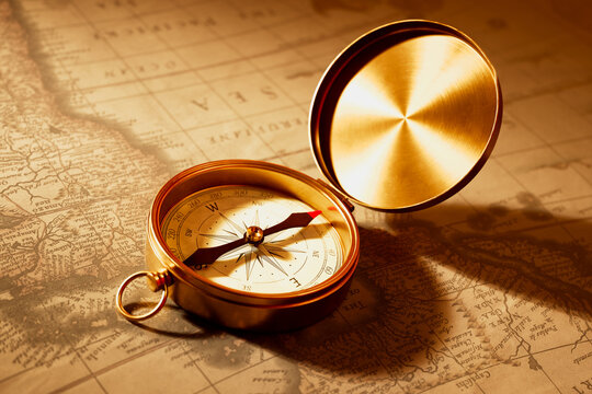 Close-Up View of a Vintage Gold Compass Resting on an Aged, Weathered Map