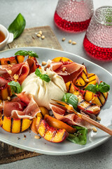 Salad with grilled peaches, mozzarella, prosciutto ham, basil, for wine. vertical image. top view. copy space for text