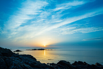 The sun rising over the Isle of Arran with a coastal cloudscape over Ardnacross Bay viewed from a...