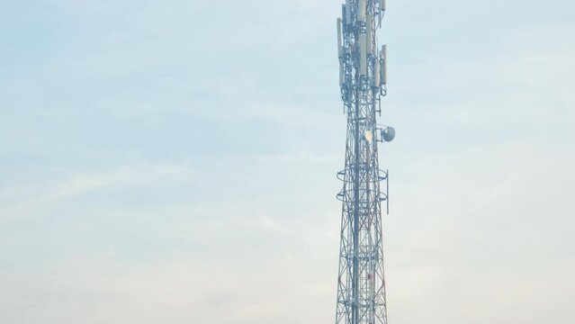 Panning shot of cell phone signal transmitting towers stand tall in the middle of rice fields and near houses in rural Jember Indonesia on a misty morning