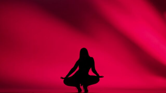 Woman silhouette dancing heels dance in a studio. Bright red neon light, shadowed background. Black sexy costume, high heels. Modern sensual choreography. Full length.