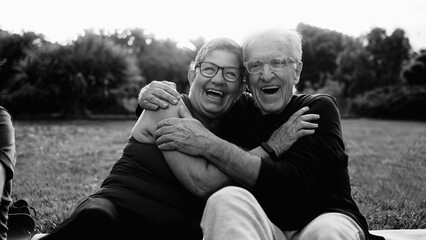 Happy senior couple having fun smiling in Park City. Older people enjoy together outdoors in nature. Black and white editing - obrazy, fototapety, plakaty
