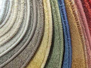 Texture of many different colored carpet samples overlayed one on top of the other