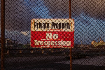 a sign posted on the chain link fence outside an industrial zone