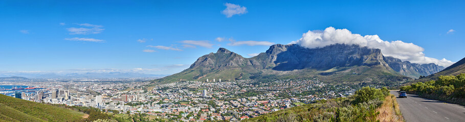 Fototapeta na wymiar City landscape near mountains with a cloudy blue sky background on a sunny summer day. Beautiful cityscape of Cape Town, South Africa as a travel vacation or holiday destination in a coastal location