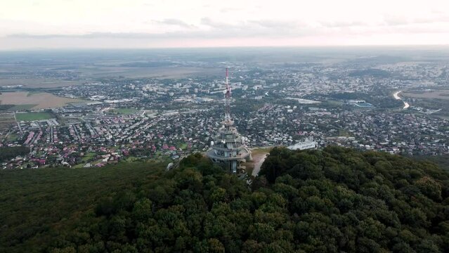 4k aerial footage of transmitter tower on Zobor Hill in Nitra - Slovakia.  Flight by drone over the hill and large city near forest.