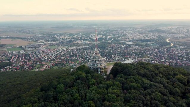 4k aerial footage of transmitter tower on Zobor Hill in Nitra - Slovakia.  Flight by drone over the hill and large city near forest.
