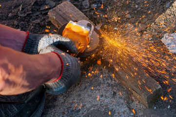 Bright sparks of metal fly from the disk of an angle grinder. A power tool in the hands of a worker...