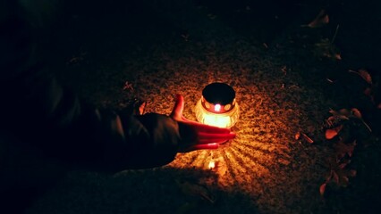 Anonymous Person Putting Lit Vigil Candle Lantern on Cemetery Grave Tombstone All Saints Day Evening