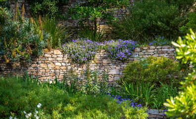 Petit jardin fleuri et muret en pierre aménagé au printemps.