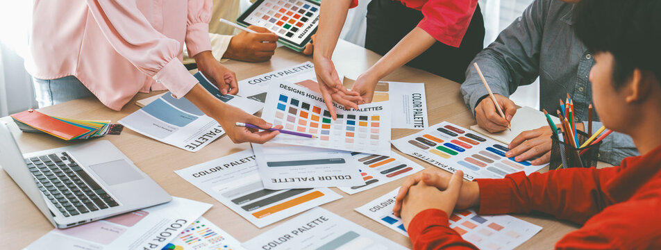 Professional architect designer team brainstorm about color selection while skilled interior design using tablet displayed color palette with color palette document scatter around. Variegated.