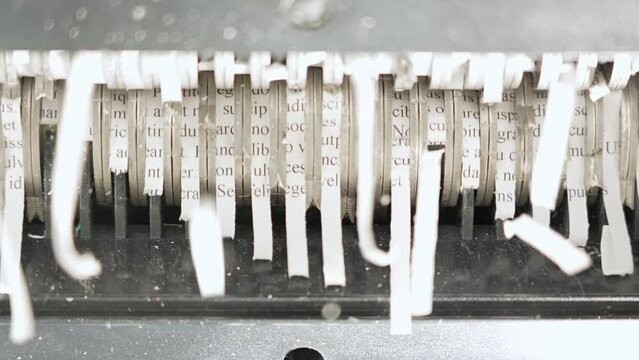Teeth of the shredder rotating and destroying paper lorem ipsum text. Paper shredder machine used to cut secret documents with sensitive information, confidential, personal financial information.