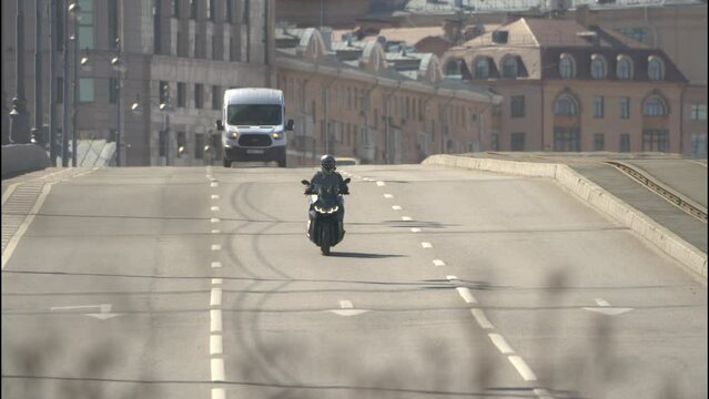 A motorcyclist crosses a road bridge in the city. A man on a modern motorcycle and in special clothes rides on a bridge. S-log3