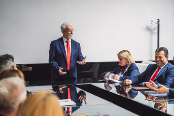 Experienced, mature businessman working with his senior employees in a good atmosphere at the office. Senior business people joking at having fun during meeting at work.