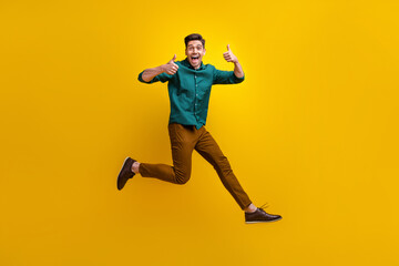 Photo of attractive nice man dressed trendy clothes running empty space showing thumb up cool feedback isolated on yellow color background