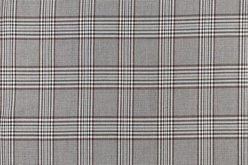 The texture of a black and brown tartan checkered fabric. Material for sewing skirts, shirts and clothes. Background for your mockup. Traditional Scottish clothing.