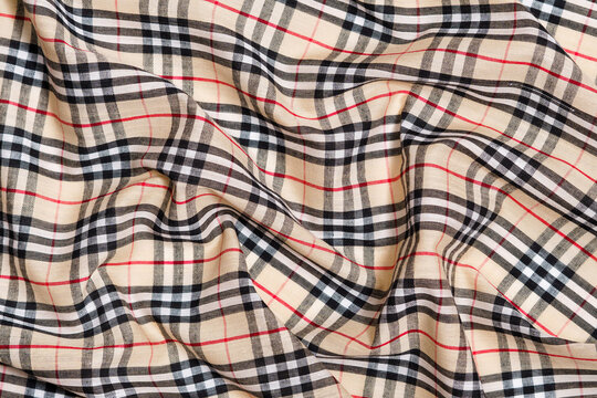 Crumpled Burberry tartan fabric texture in beige, red and black. Background for your design October 26, 2023 in Kyiv, Ukraine.
