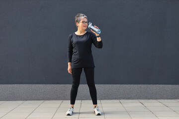 A fit and healthy woman in sportswear taking a refreshing water break during an urban run, exuding beauty and athleticism.