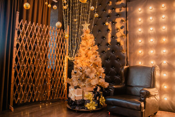 Christmas decoration, chair and tree with black balls and gifts. Interior decoration for the holiday with golden toys. fires. bokeh