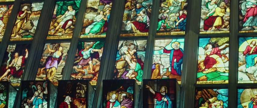 Biblical historical events in colorful pictures on stained glass windows in the cathedral. Ancient art in the Basilica church.