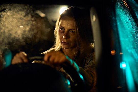 Woman with bruises driving a car at night