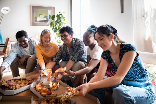 Young diverse friends having pizza at home