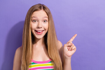 Photo of impressed schoolgirl with straight hairdo dressed striped top indicating at discount empty space isolated on violet background