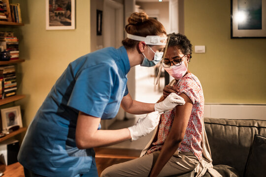 Young caregiver vaccinating a senior patient at home