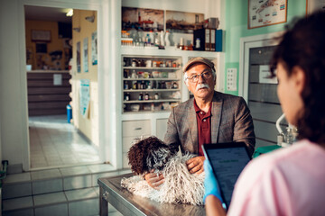 Senior man bringing his dog to the veterinarian at the clinic