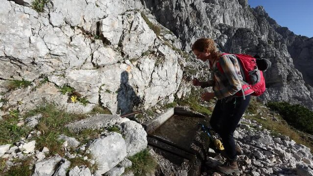 Adult Female Hiker Drinking Water from Alpine Spring in Hugh Mountains of European Alps - Kriski Podi, Julian Alps Slovenia