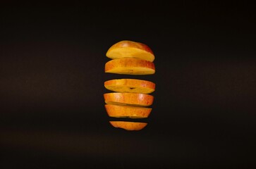 Large apple separated by cut slices on a black background