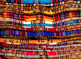 Stack of multicolored andean textile and fabrics in Pisac traditional market, Peru
 - obrazy, fototapety, plakaty