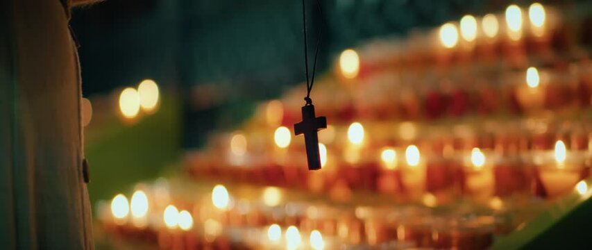 Religious cross against background of burning glowing candles in the church. Christian faith in God.