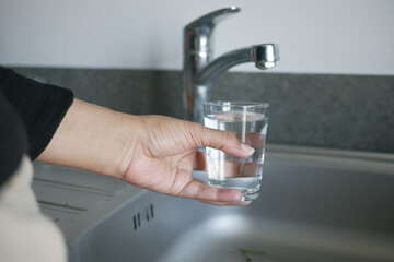  water pouring from a faucet tap in a glass, drinking pure water concept 