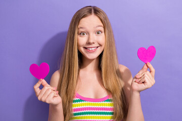 Photo of lovely schoolgirl with straight hairdo dressed striped top demonstrate heart postcards in hands isolated on violet background