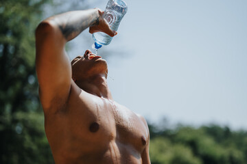Fit athlete enjoys refreshment and takes a break from outdoor training, showcasing his strong...